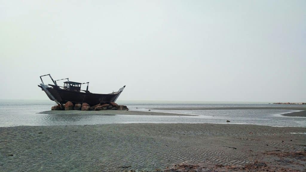 Fishing boat pulled up onto a quiet shore. Photo credit Emad Erfani